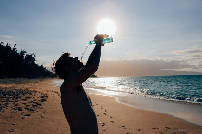 A man drinking bottled water on a sunny beach